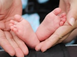 A baby’s tiny feet gently held in loving adult hands.