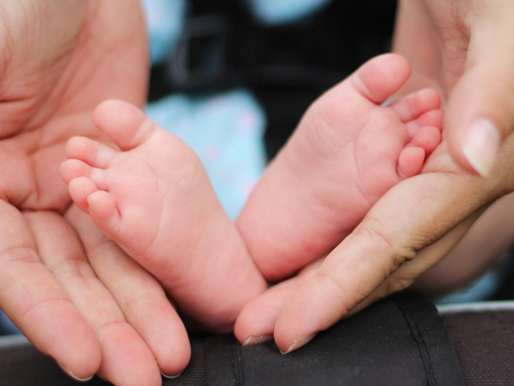 personne tenant les pieds d’un bébé