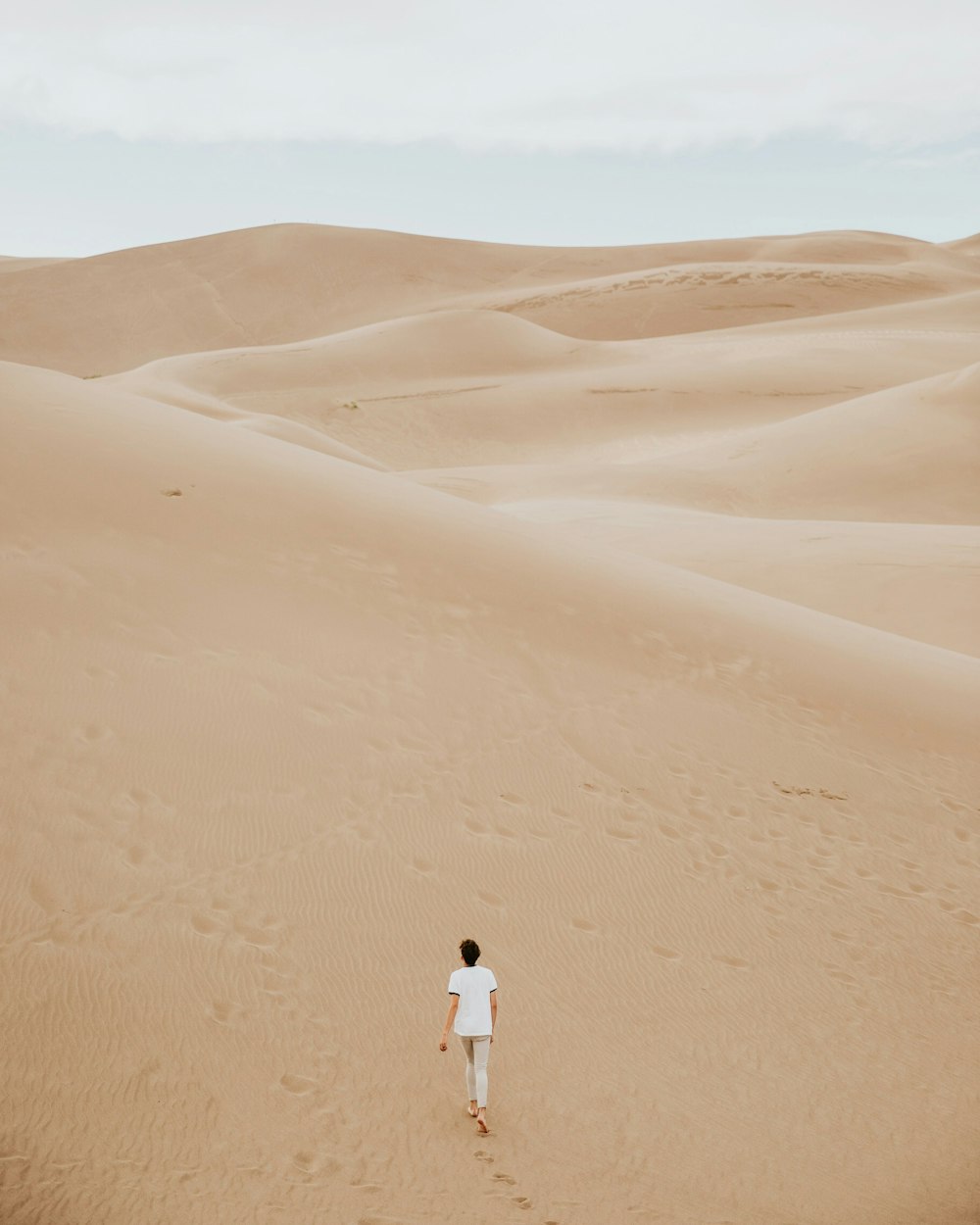 person walking on sand dune