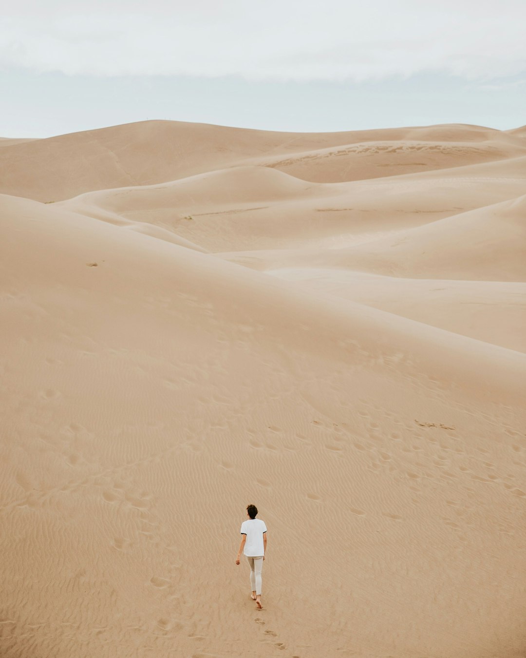 person walking on sand dune