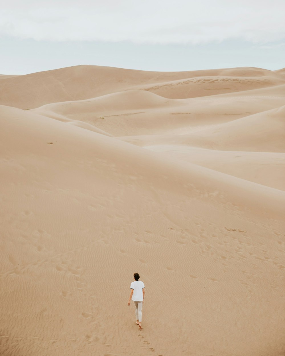 Persona caminando sobre la duna de arena