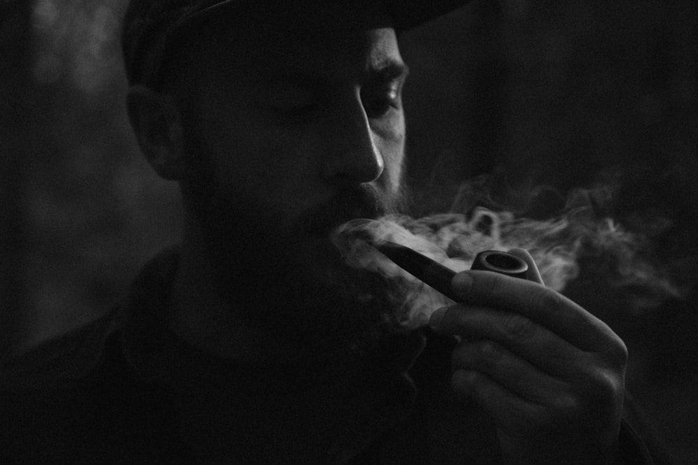 Foto en escala de grises de un hombre usando pipa de fumar