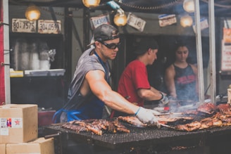 man standing infront of grill while holding tong