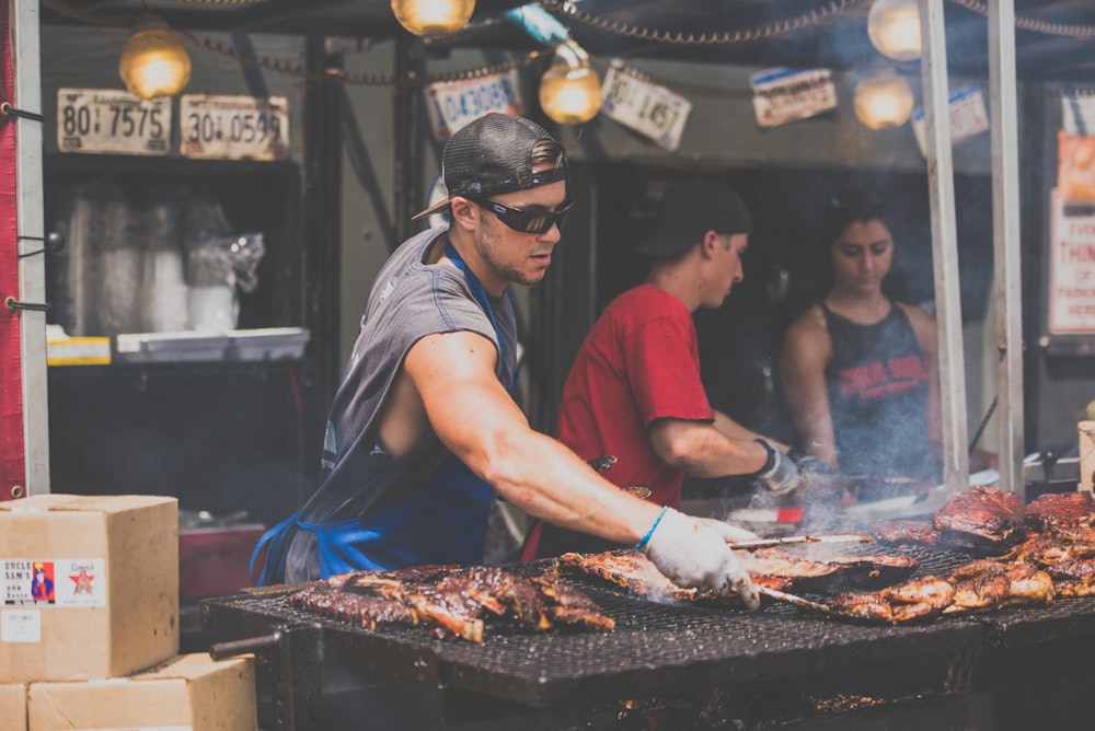 man standing infront of grill while holding tong