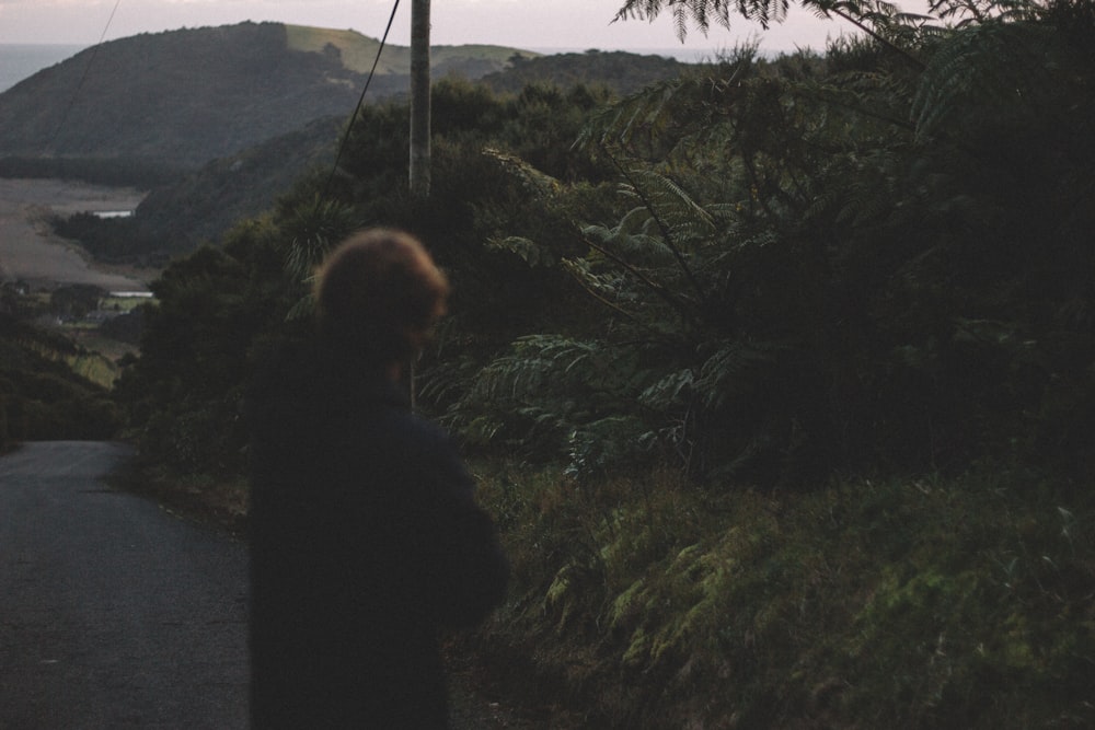 person standing on asphalt road in front of tree