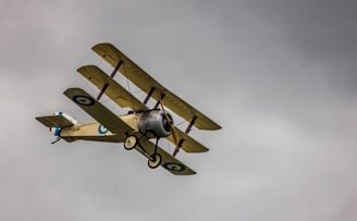 A vintage-style blueprint illustration of a WWI triplane soaring over a sepia-toned battlefield.