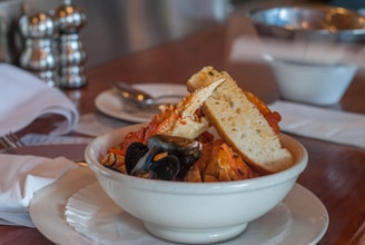 A smiling chef presenting a steaming bowl of traditional seafood stew, rich in color and aroma.