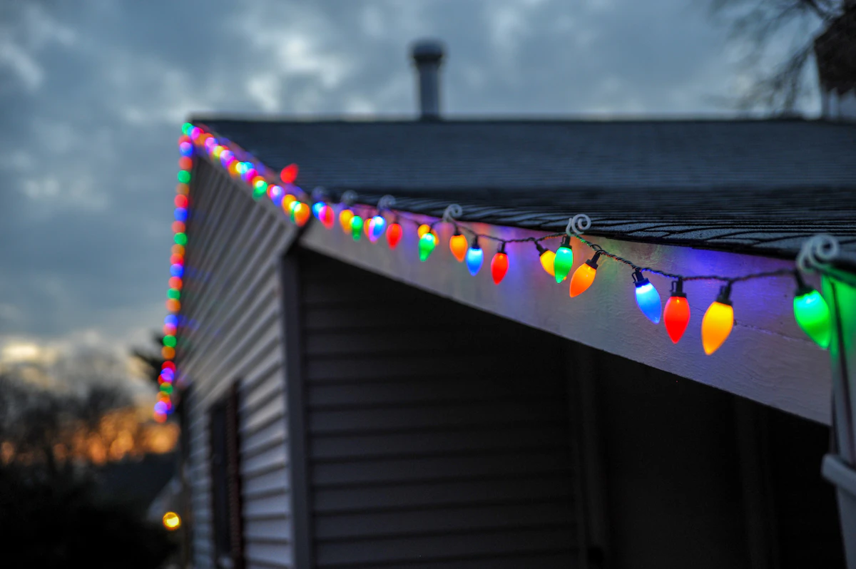 Close-up of large multicolor C9 bulb lights installed along a roofline at dusk