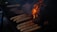 A barbecue grill with several sausages and burger patties cooking over open flames and darkened areas of smoke.