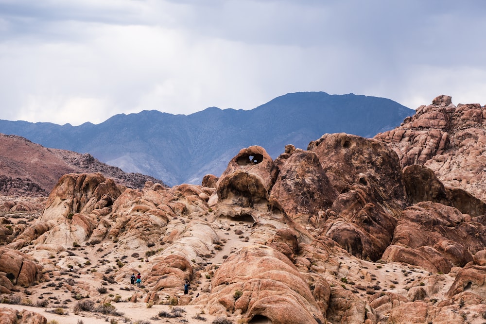 brown rock formation near mountain under cloudy sky