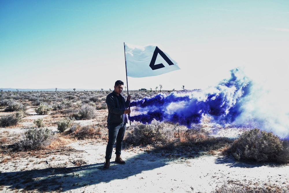A man holding a flag with smoke surround him.