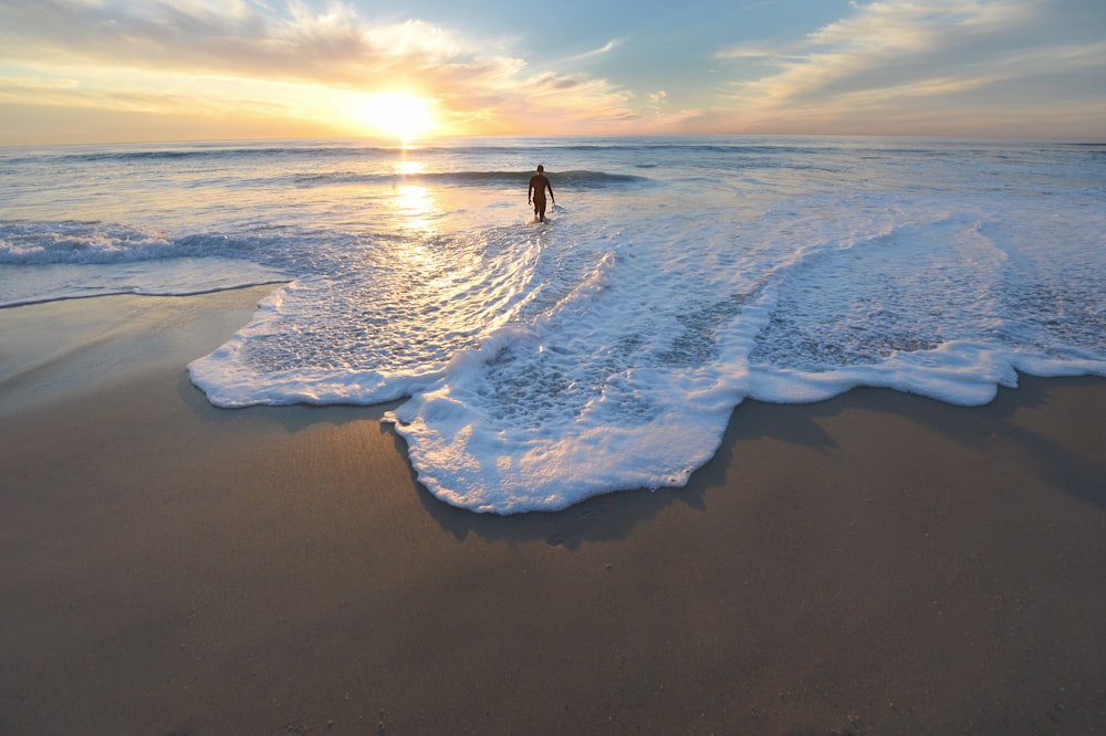 man standing on seashore during sunset