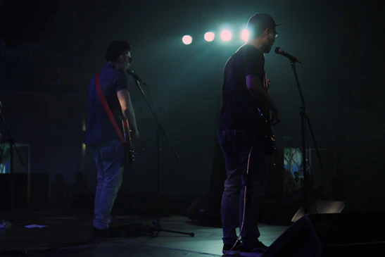 Close-up shot of the duo harmonizing with their guitars under soft spotlight.