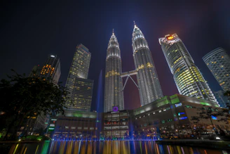 Night view of the illuminated twin towers reflecting off the glass façade.