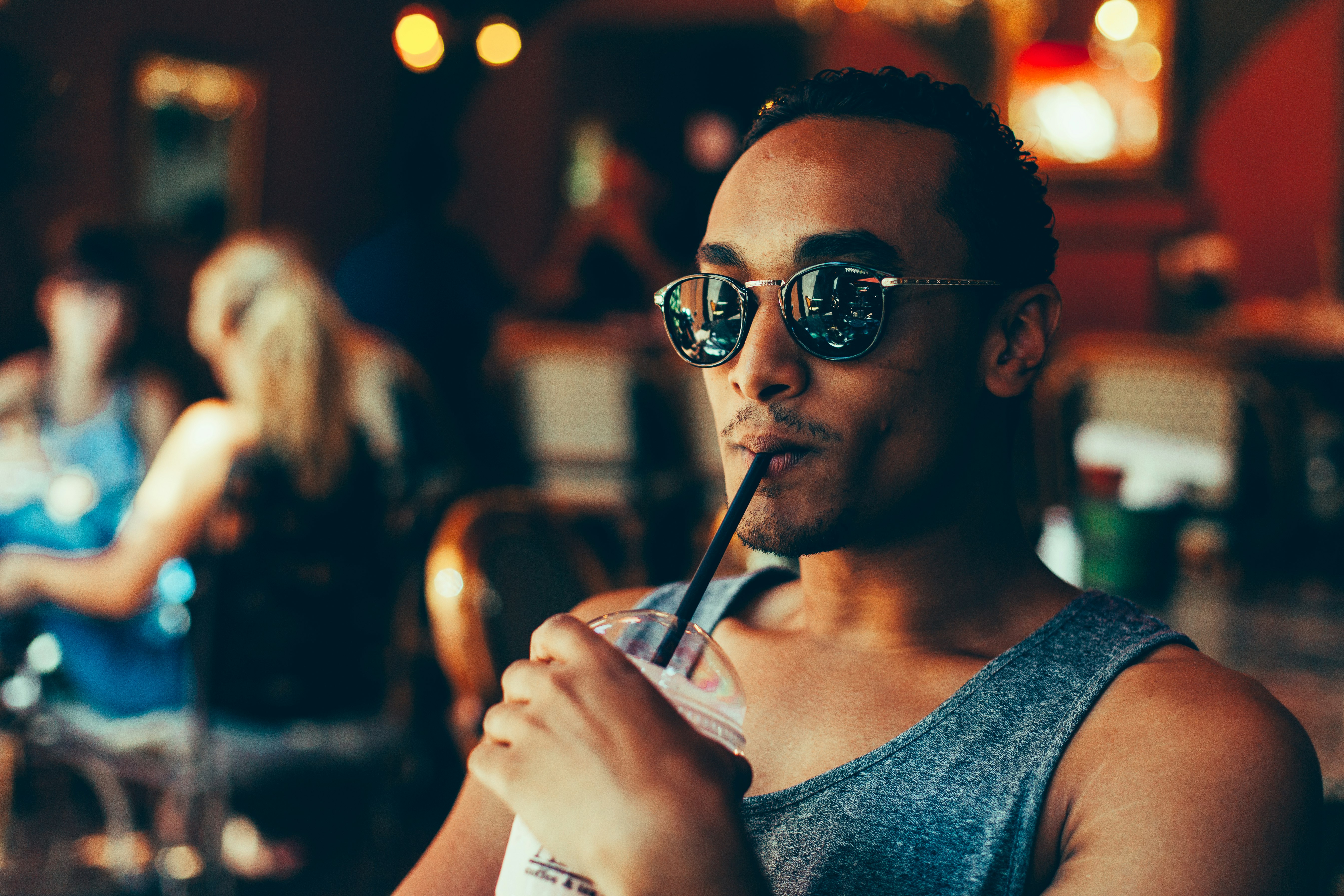 Man wearing sunglasses drinking an iced coffee