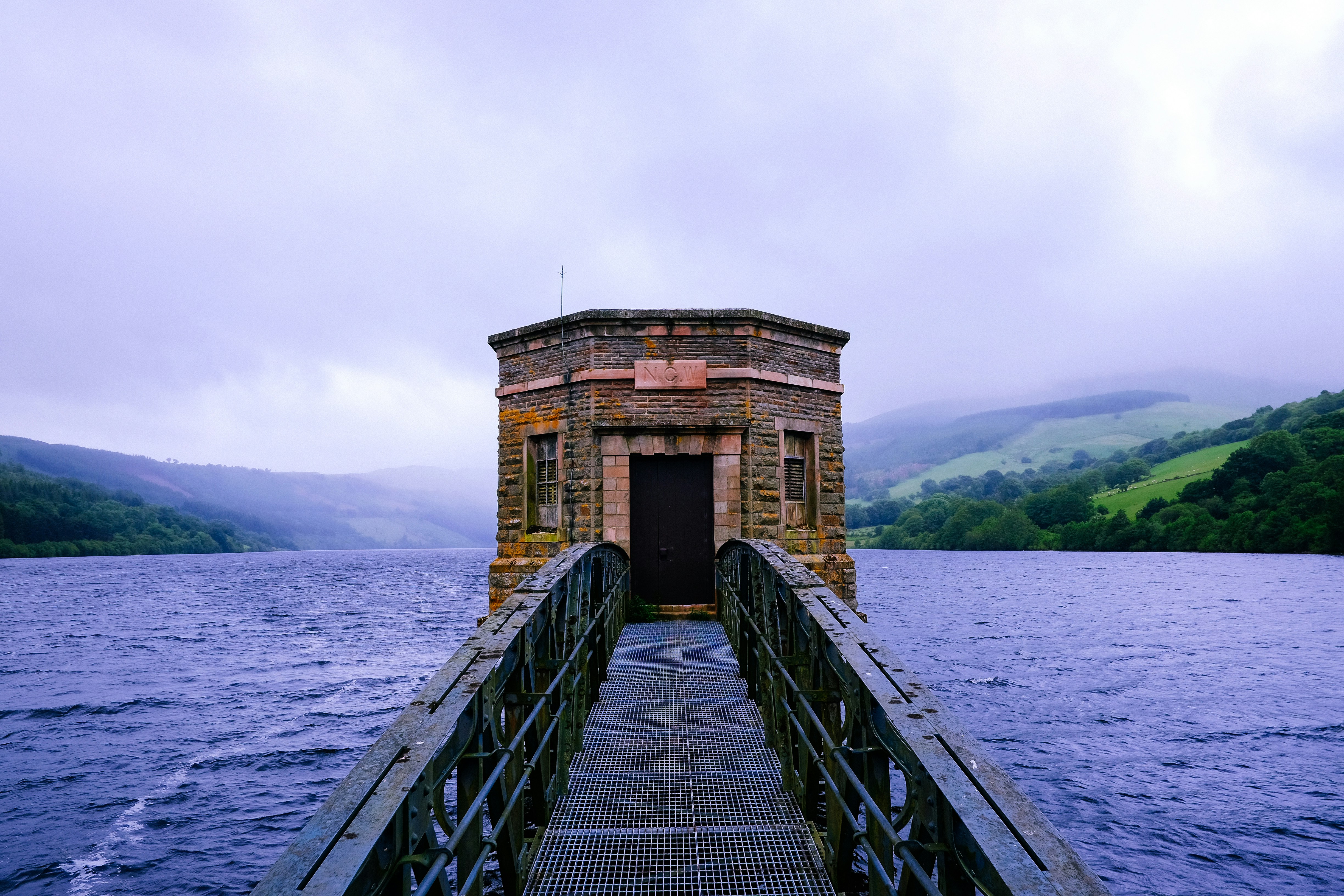 black metal bridge leading to building surrounded by water