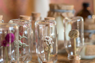 A close-up of amber glass bottles filled with golden fragrance oils surrounded by fresh flowers and herbs.
