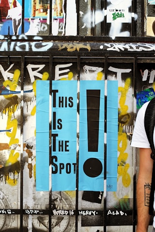 A wooden fence painted with the words "This Is The Spot!"