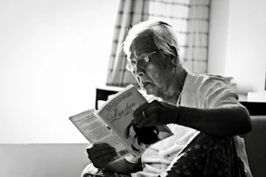 A calm and cozy living room setting where an elderly person is reading a book.