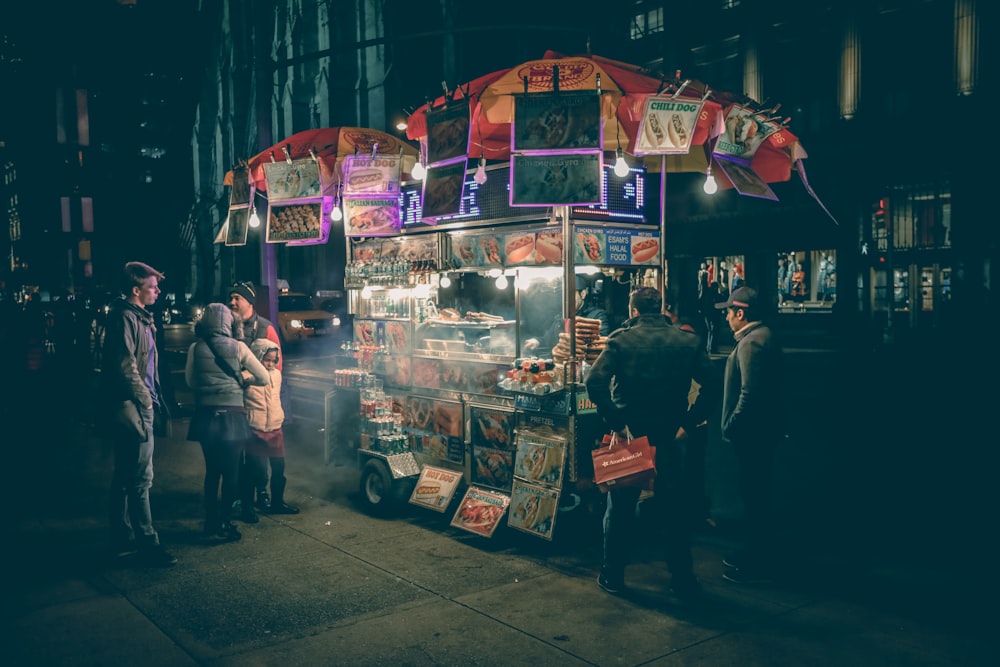 group of people standing near food cart