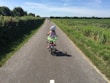 A smiling child wearing a colorful, snug-fitting safety helmet while riding a bike in the park.