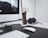A modern and minimalistic workspace featuring a large computer monitor, a smartphone in a dock, and a pair of headphones on a sleek desk. The setup includes a wireless keyboard and mouse, along with a small speaker and other tech accessories.