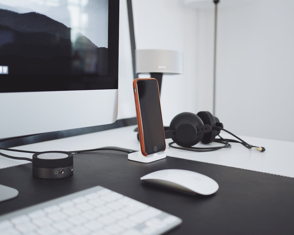 black iPhone charged on table near black headphones