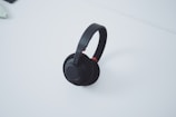 Photo of a sleek wireless headphone set in black, styled on a minimalist white table.