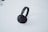 A pair of black over-ear headphones resting on a white surface. The headphones have cushiony ear pads and a sleek headband with a minimalist design.