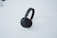 A pair of black over-ear headphones resting on a white surface. The headphones have cushiony ear pads and a sleek headband with a minimalist design.