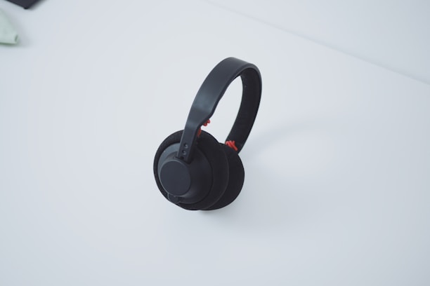 A stylish wireless headphone set resting on a minimalist white desk.