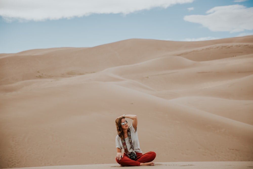 minimalist photography of woman sitting on desert ground