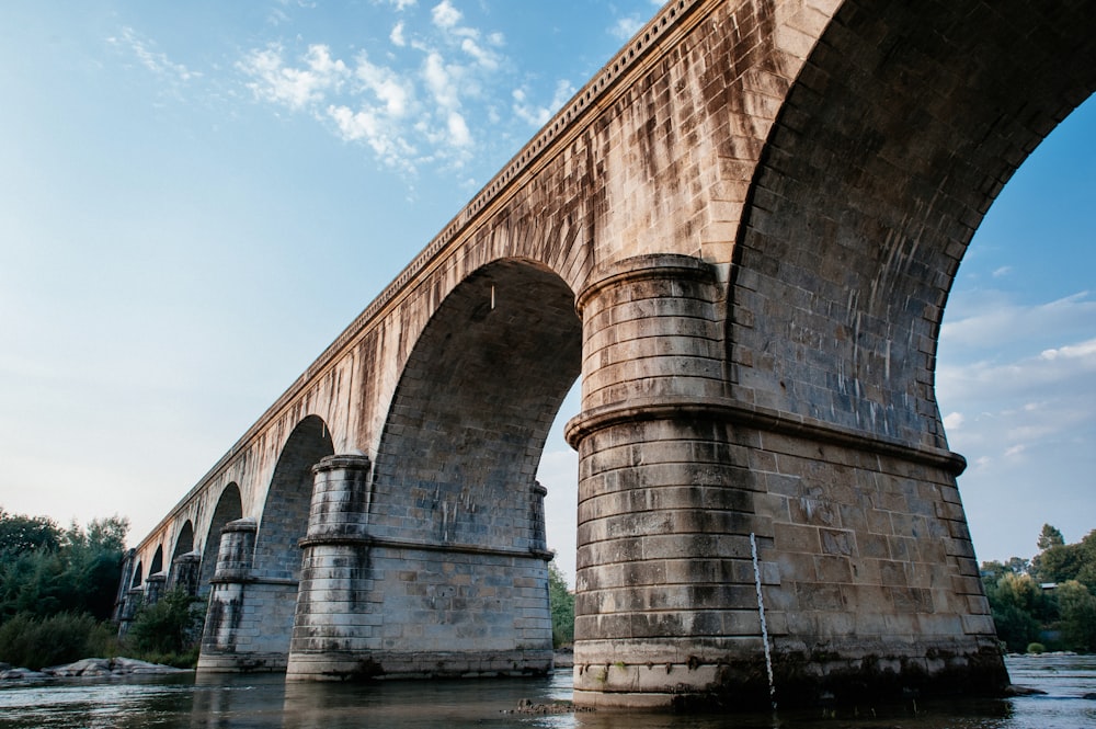 brown concrete bridge over river under blue sky during daytime