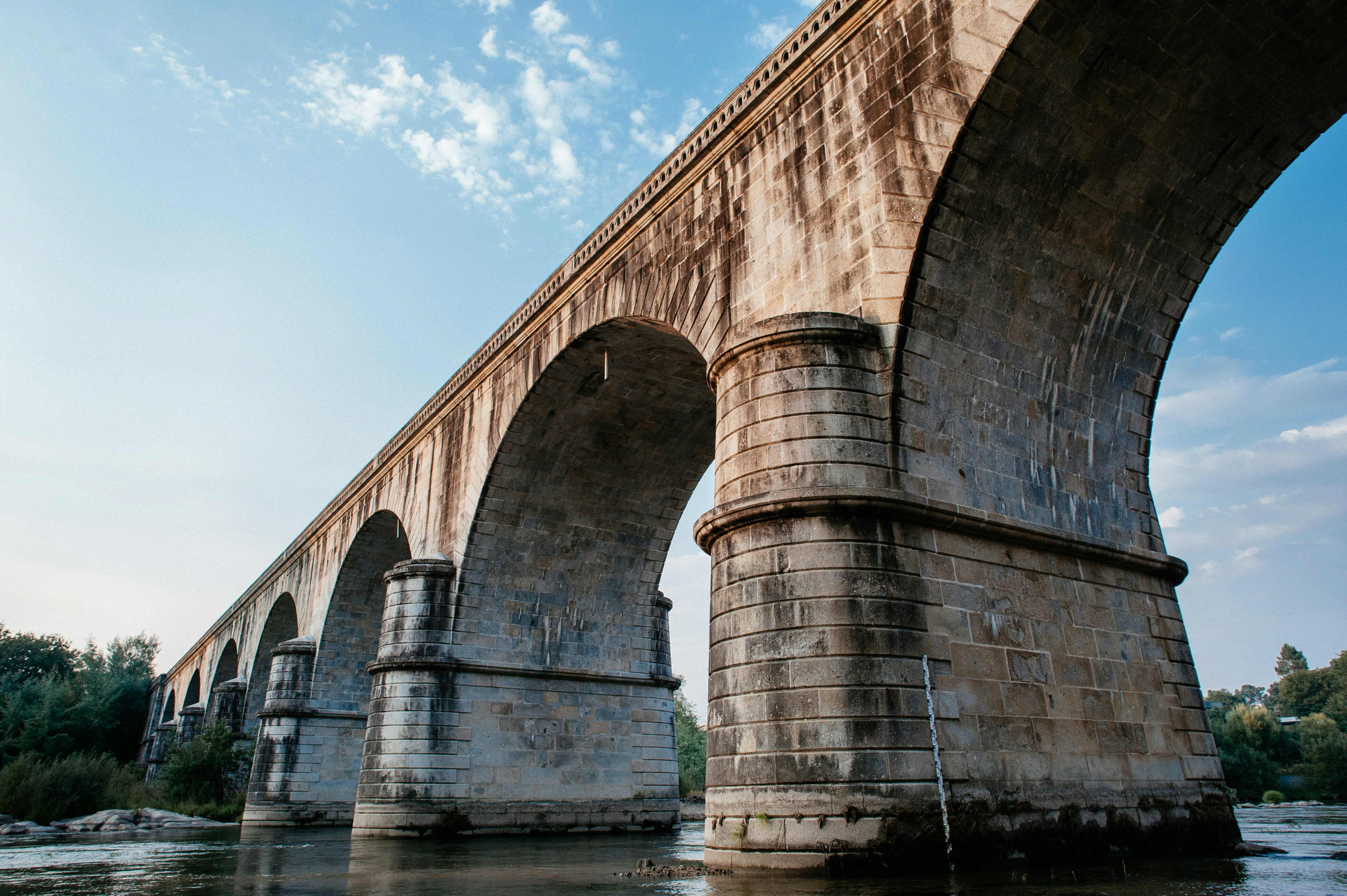 brown concrete bridge over river under blue sky during daytime