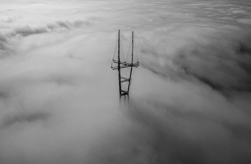 foto in scala di grigi della torre circondata da nuvole