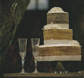 two clear wine glasses beside 3-layer towel cake