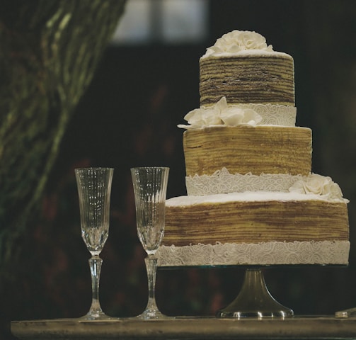 two clear wine glasses beside 3-layer towel cake