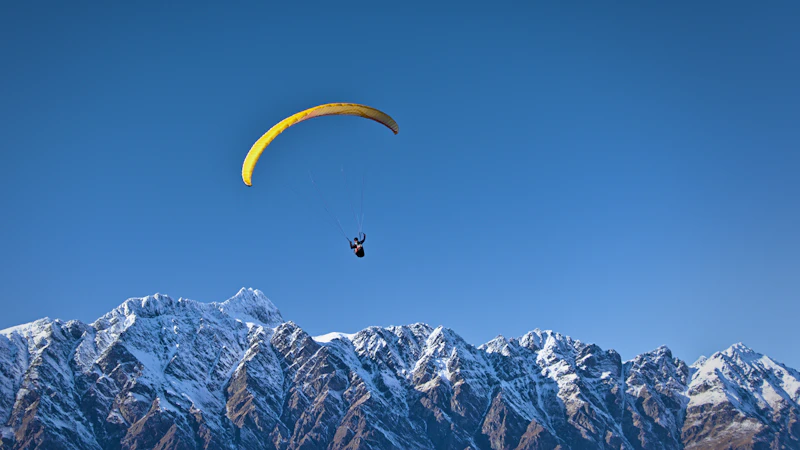 Paraglider flying above snow-capped mountains