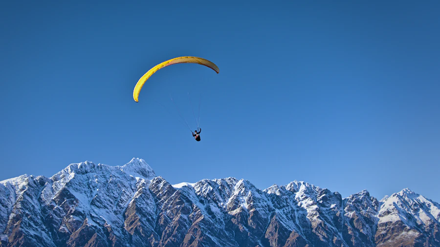 Paraglider flying above snowy mountains