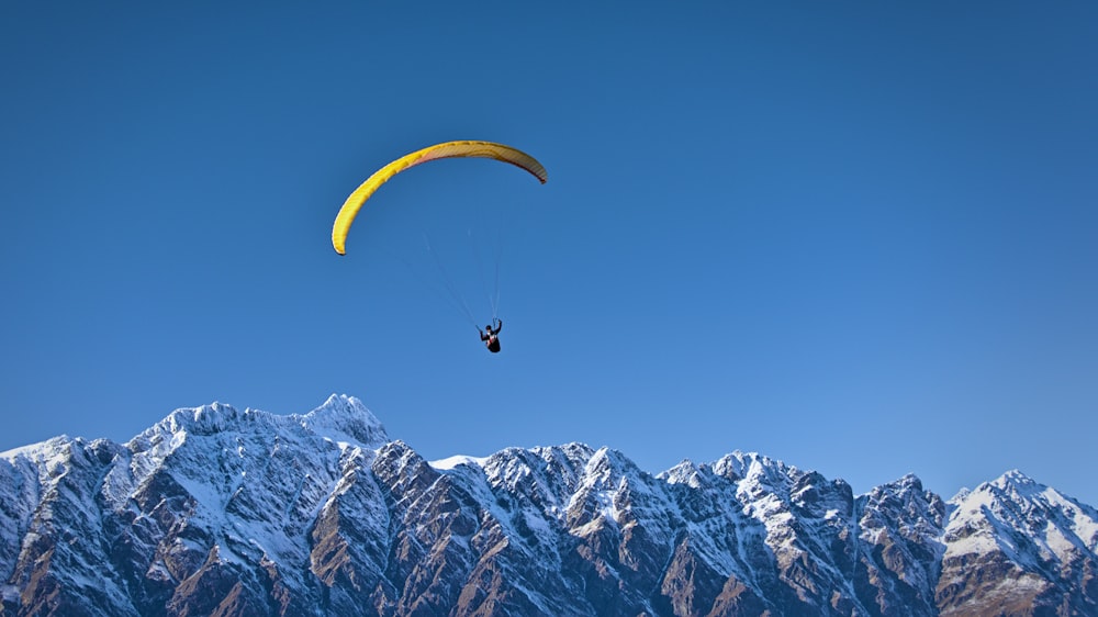 uomo sul paracadute vicino alla montagna