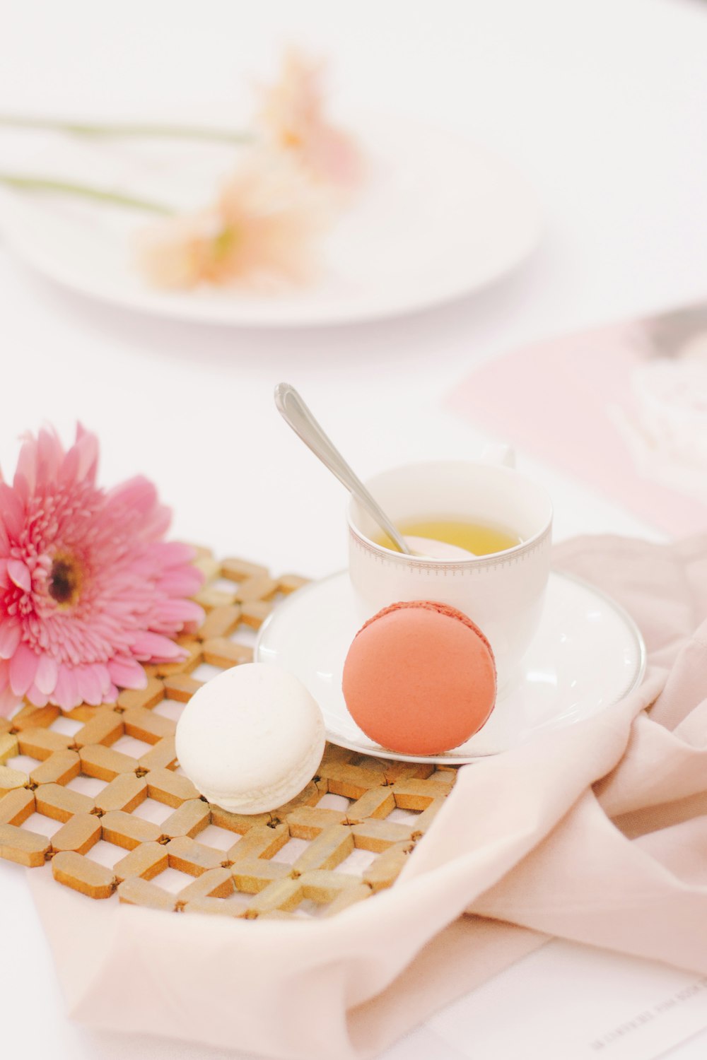 two orange and white macaroons beside white ceramic cup with spoon
