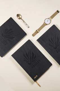 Eliz watch displayed elegantly beside a gold pen and black leather notebook.