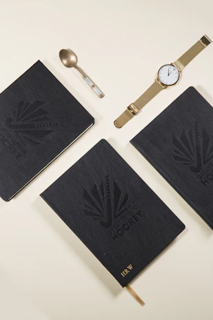 Eliz watch displayed elegantly beside a gold pen and black leather notebook.