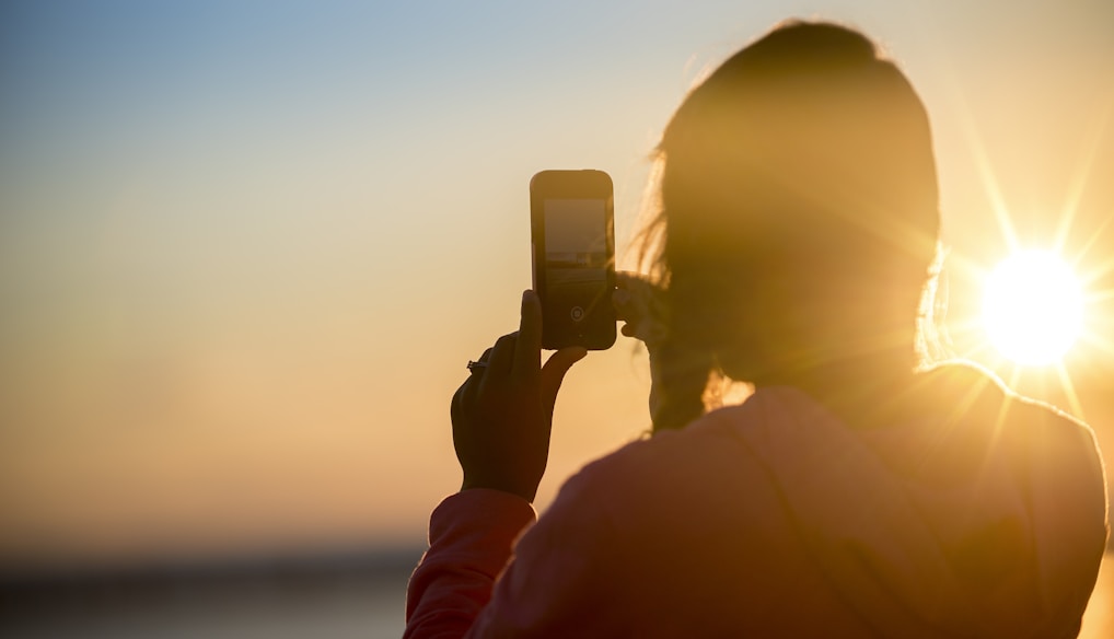 woman taking photo of sunset