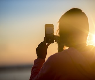 woman taking photo of sunset