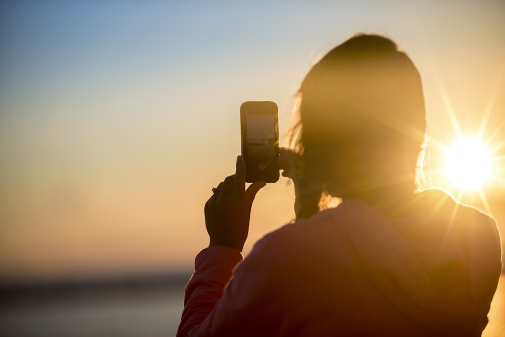 femme prenant une photo du coucher du soleil