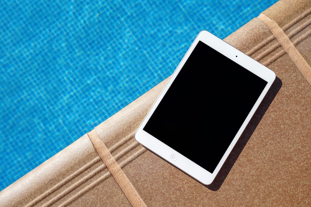iPad blanco al lado de la piscina