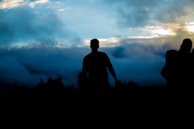 silhouette of person walking towers trees
