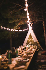 A beautifully set long table outdoors with guests enjoying a shared meal under soft string lights.