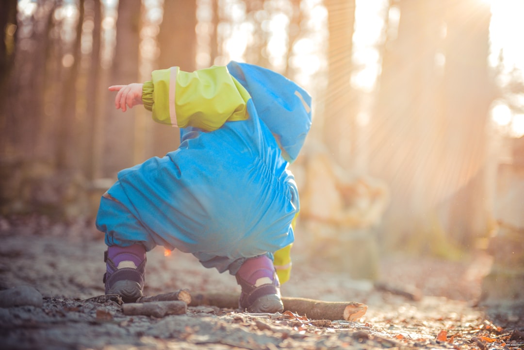 toddler picking up tree branch,